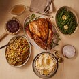 Roasted whole turkey with stuffing, mashed potatoes, green beans, gravy and cranberry sauce for a holiday dinner.